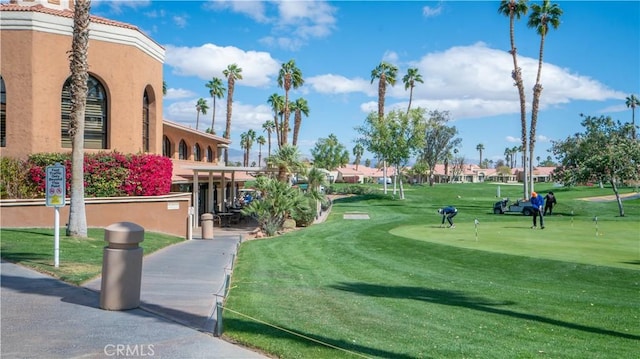 view of property's community with golf course view and a lawn