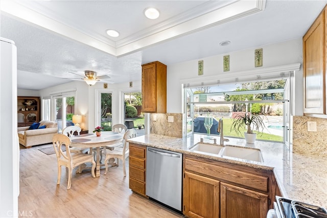 kitchen featuring backsplash, dishwasher, light wood-style floors, brown cabinetry, and a sink