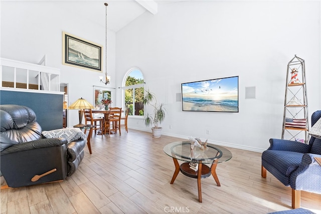 living area featuring beam ceiling, a notable chandelier, baseboards, and light wood finished floors