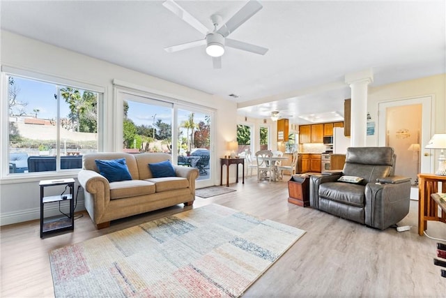 living area featuring a healthy amount of sunlight, a ceiling fan, and ornate columns