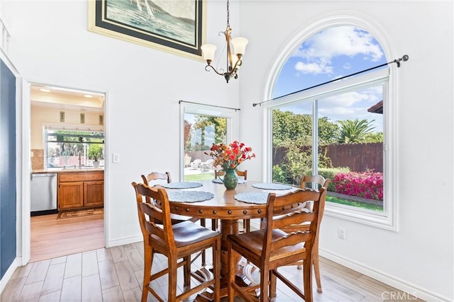 dining area with light wood finished floors, a chandelier, and a towering ceiling