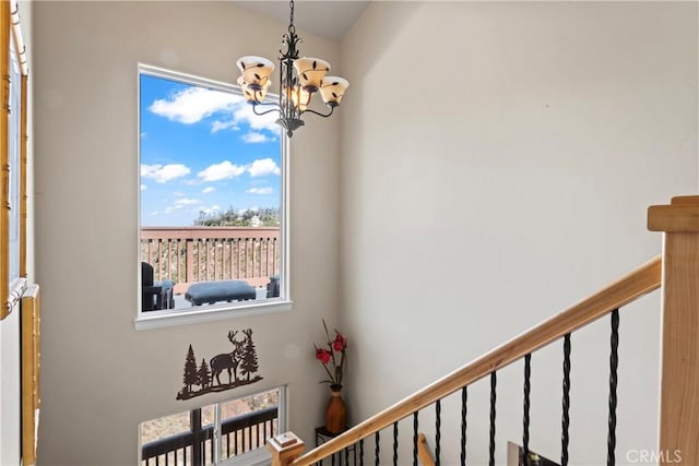 stairway featuring a notable chandelier