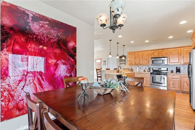 dining space featuring recessed lighting, light wood-style floors, and a chandelier