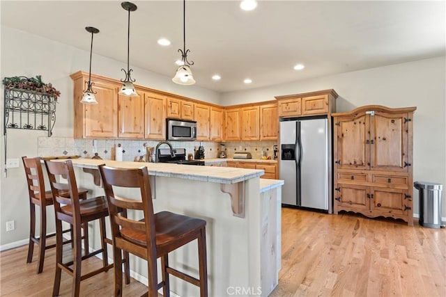 kitchen with a breakfast bar, a peninsula, light wood-style floors, and stainless steel appliances