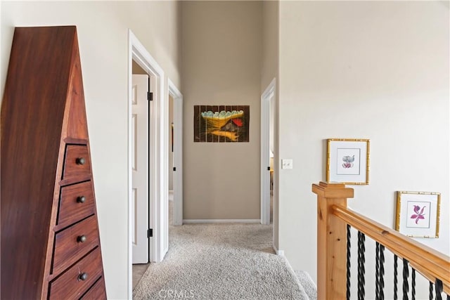 hall with baseboards, carpet floors, and an upstairs landing