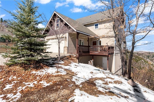 view of snowy exterior featuring a shingled roof and a garage