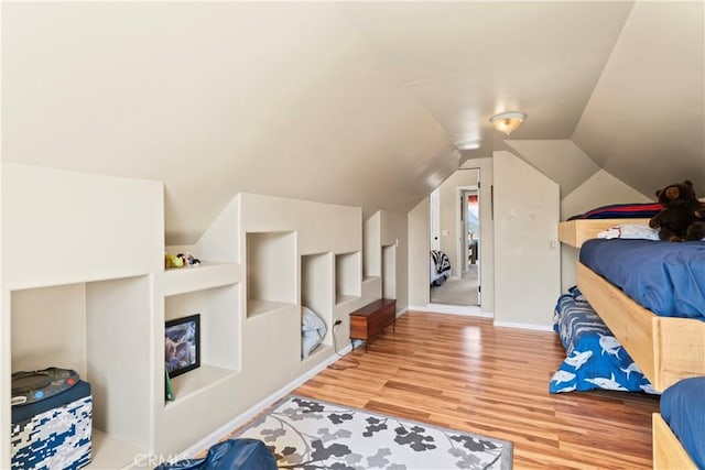 bedroom featuring baseboards, lofted ceiling, and wood finished floors