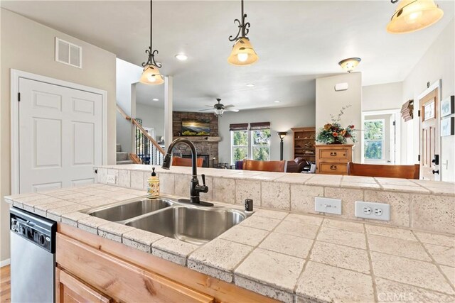 kitchen featuring visible vents, open floor plan, a fireplace, light countertops, and dishwasher