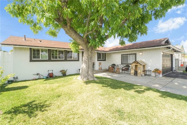 back of property with fence, a lawn, a garage, and stucco siding