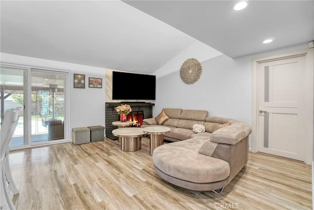 living room featuring lofted ceiling, recessed lighting, a fireplace, and light wood-type flooring