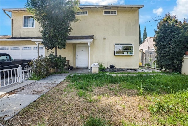 view of property featuring fence, a garage, and stucco siding