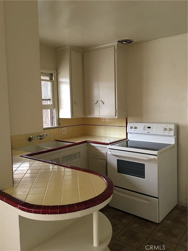 kitchen with tile countertops, backsplash, a peninsula, and electric stove