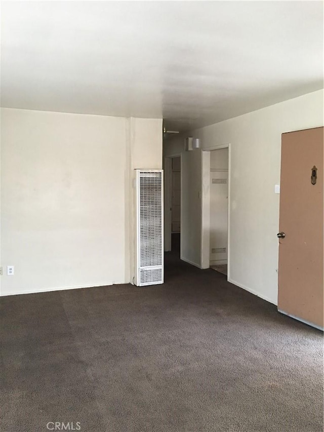 spare room with dark carpet and a heating unit