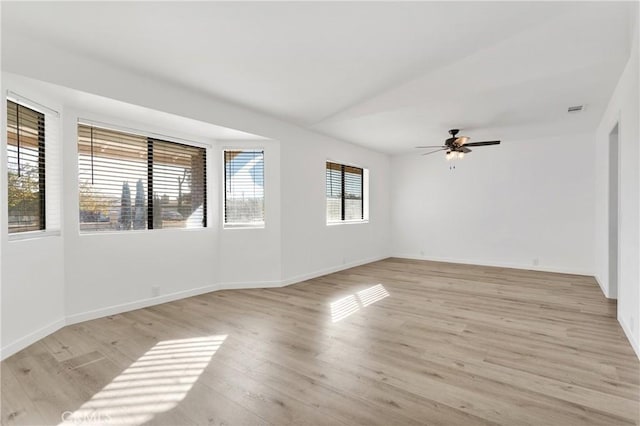 empty room featuring a ceiling fan, baseboards, visible vents, light wood-style flooring, and vaulted ceiling