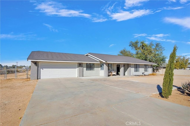 single story home featuring a garage, brick siding, concrete driveway, and fence