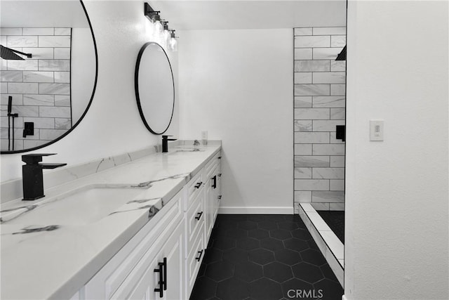 full bath with a sink, baseboards, tiled shower, and double vanity