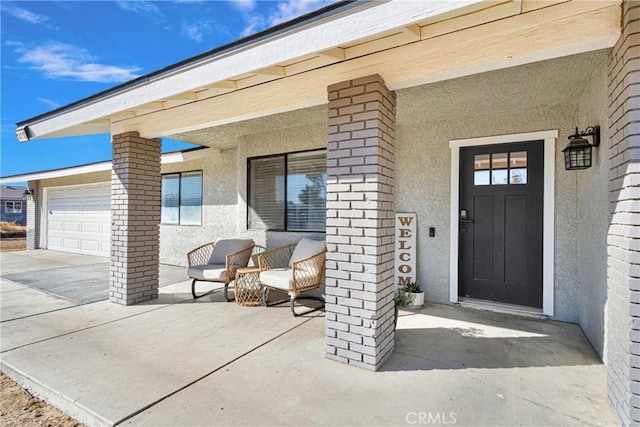 property entrance featuring stucco siding, covered porch, and an attached garage