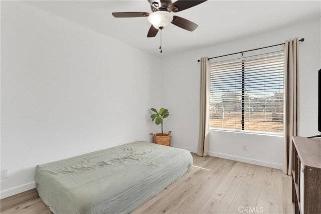 bedroom with baseboards, light wood finished floors, and ceiling fan