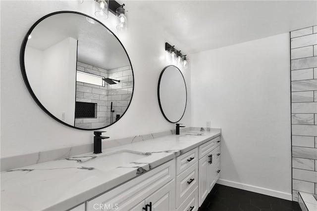 full bath featuring double vanity, tiled shower, baseboards, and a sink