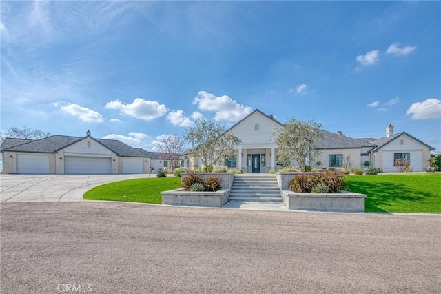 view of front of house with a garage, concrete driveway, and a front lawn