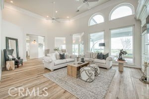 living area with ceiling fan, ornamental molding, recessed lighting, a high ceiling, and wood finished floors
