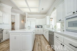 kitchen with a kitchen island, white cabinets, light wood finished floors, white microwave, and dishwasher