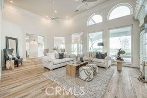 living room with wood finished floors, a high ceiling, recessed lighting, ceiling fan, and crown molding