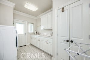 kitchen with white cabinetry, fridge, crown molding, light countertops, and light tile patterned floors