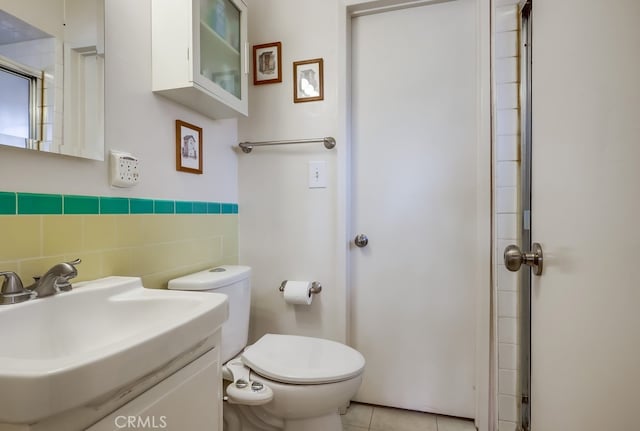 bathroom with tile patterned flooring, tile walls, toilet, and vanity