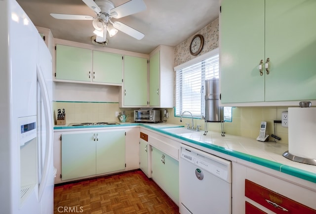 kitchen featuring tasteful backsplash, a toaster, tile countertops, white appliances, and a sink