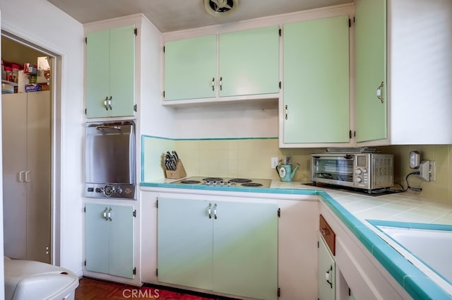 kitchen with a toaster, backsplash, white electric stovetop, and visible vents