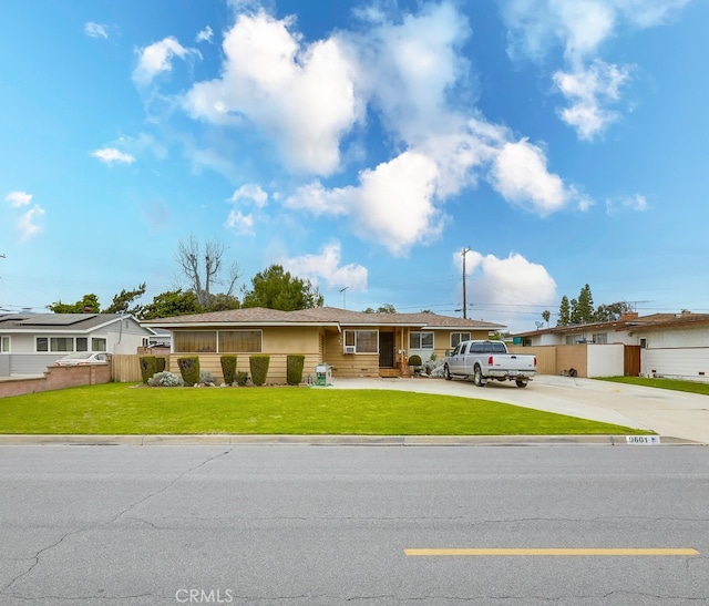 ranch-style house featuring a front yard, concrete driveway, and fence