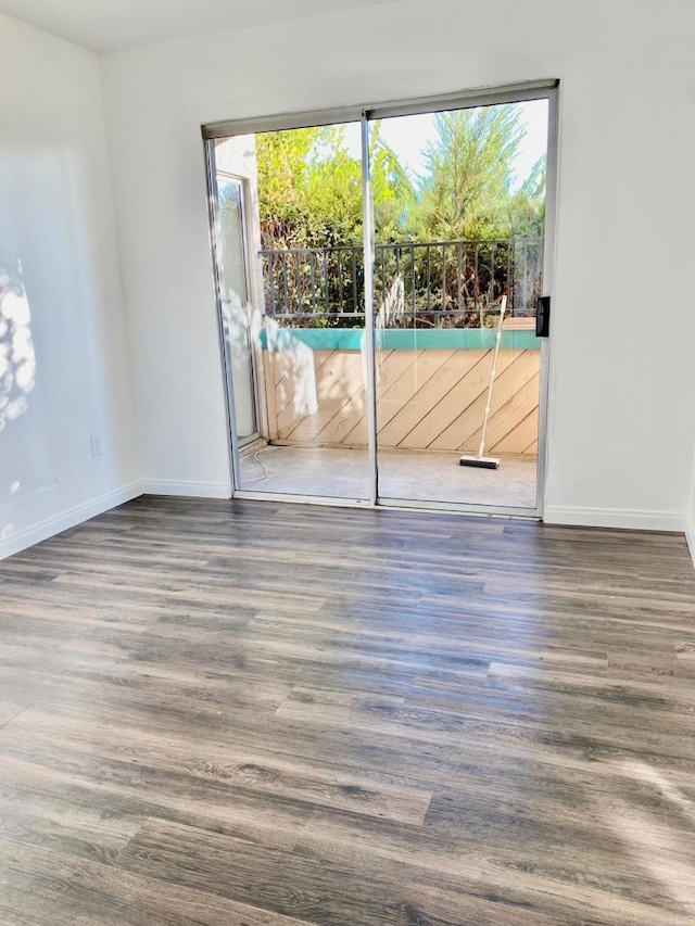 spare room featuring baseboards and wood finished floors