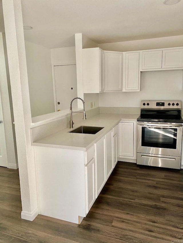 kitchen featuring a sink, dark wood-style floors, white cabinetry, stainless steel electric range, and light countertops