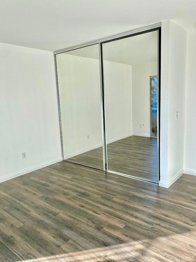 unfurnished bedroom featuring a closet, baseboards, and wood finished floors