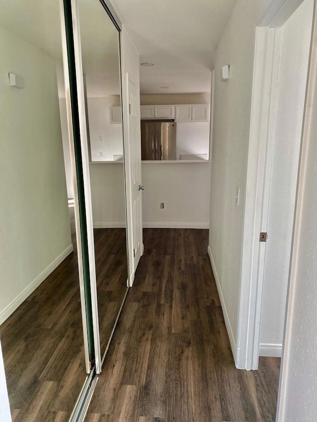 corridor with dark wood-style floors and baseboards