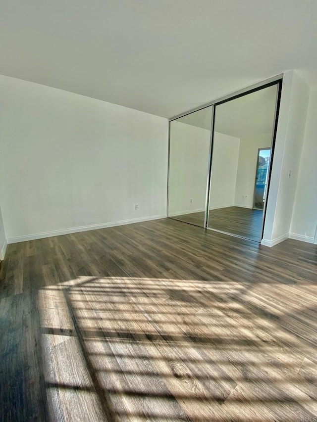 interior space featuring dark wood-style floors, baseboards, and a closet