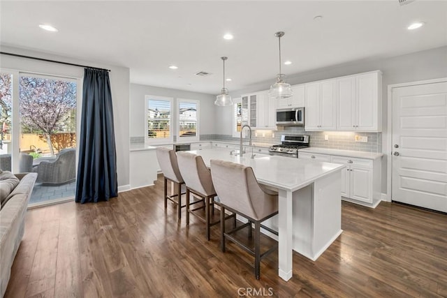 kitchen with dark wood-style floors, decorative backsplash, appliances with stainless steel finishes, and light countertops