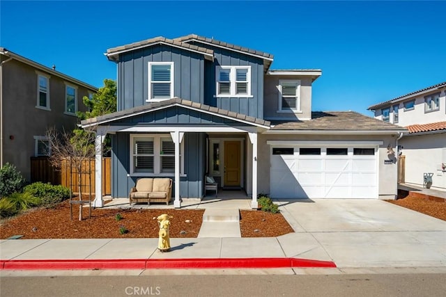 traditional home with board and batten siding, fence, a porch, concrete driveway, and a garage