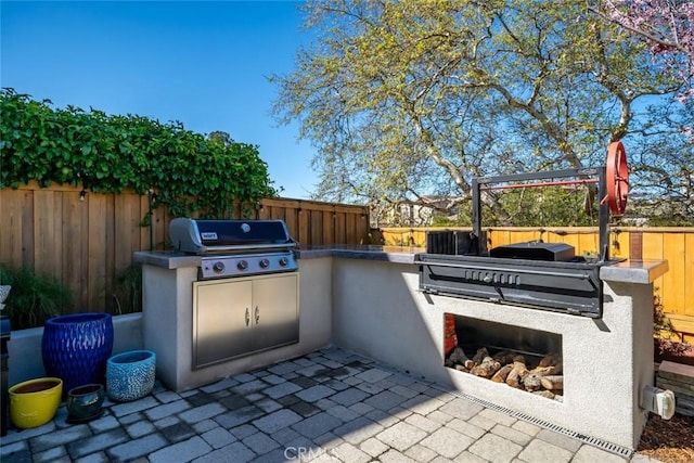 view of patio / terrace featuring exterior kitchen, a fenced backyard, and a grill