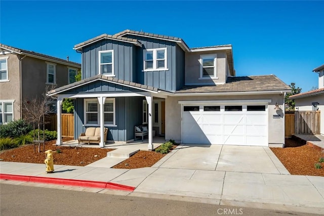 traditional-style home featuring a porch, driveway, board and batten siding, and fence