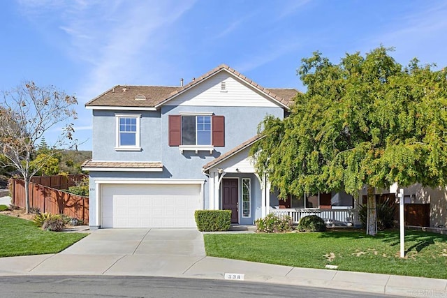 traditional-style house with a front yard, fence, a porch, an attached garage, and concrete driveway