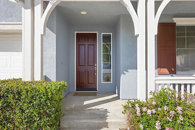 entrance to property with stucco siding and a porch