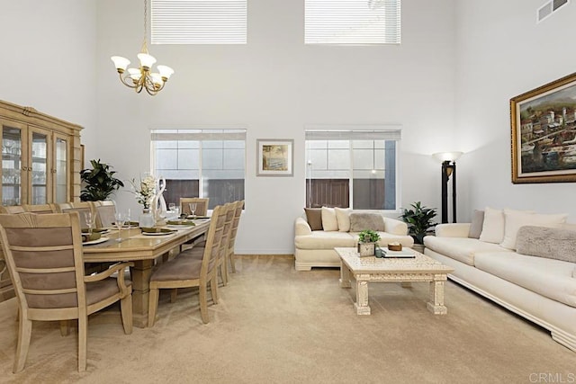 dining space with a notable chandelier, visible vents, a towering ceiling, and light carpet