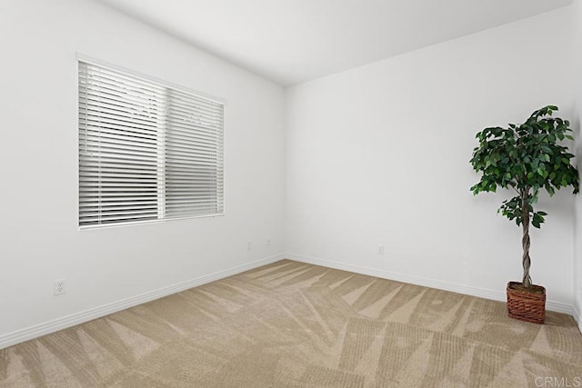 unfurnished room with baseboards and light carpet