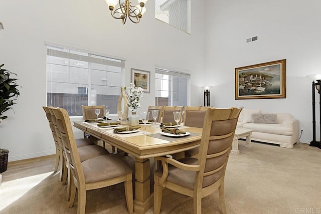 dining space featuring visible vents, baseboards, a towering ceiling, a notable chandelier, and light colored carpet