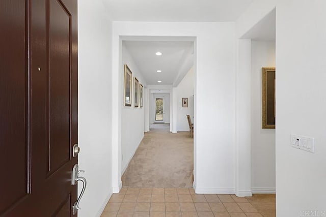 corridor featuring light tile patterned floors, recessed lighting, baseboards, and light carpet