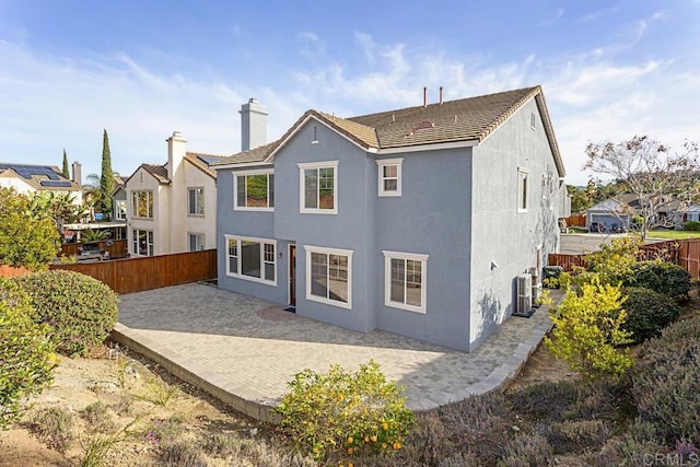 rear view of house featuring stucco siding, cooling unit, a patio, and fence