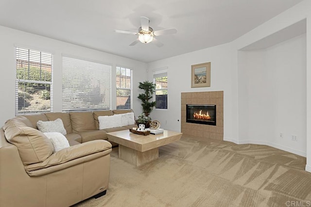 living area with a ceiling fan, light colored carpet, baseboards, and a tile fireplace