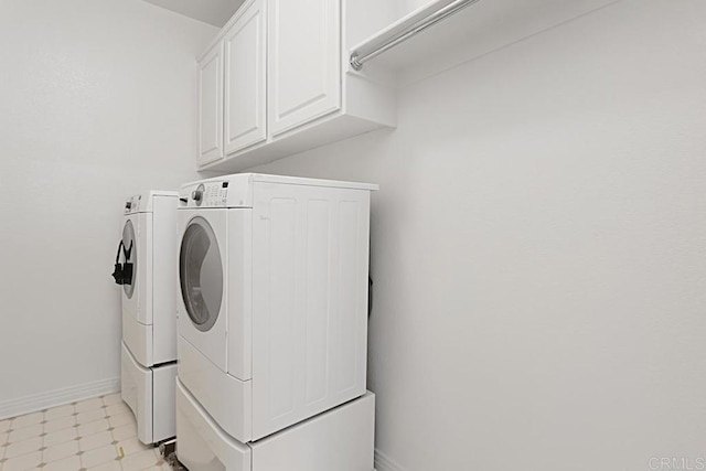 washroom with cabinet space, light floors, baseboards, and washing machine and clothes dryer